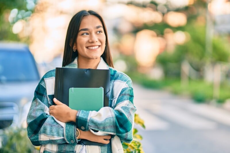 female college student holding folders and smiling