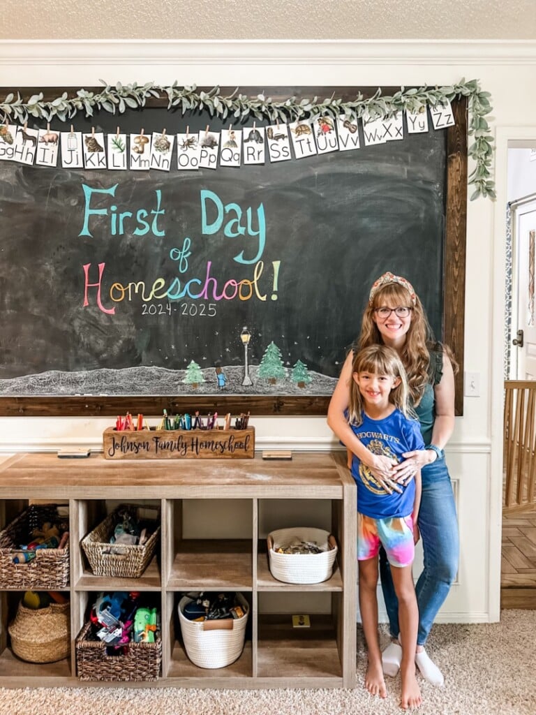 Kathryn Johnson and her daughter in front of a First Day of Homeschool sign