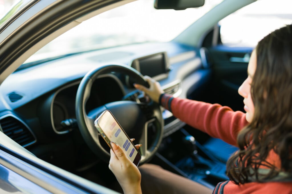 teen distracted driving, looking at cell phone in car