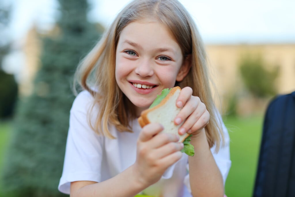 a girl holding a sandwich and smiling