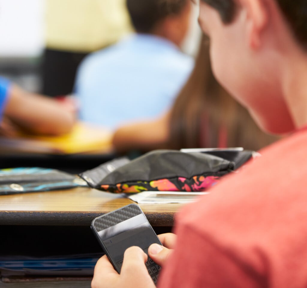 Pupil Sending Text Message On Mobile Phone In Class
