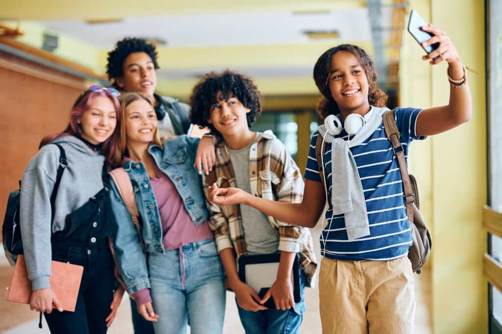 Multiracial Group Of High School Students Taking Selfie In Hallway.
