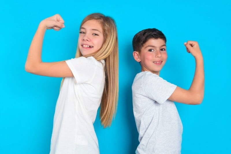 two kids smiling and flexing biceps