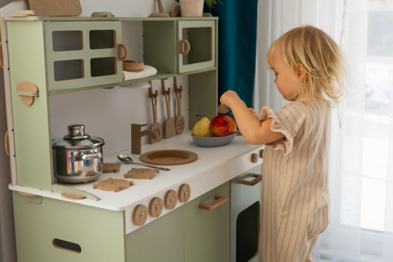toddler playing at play kitchen