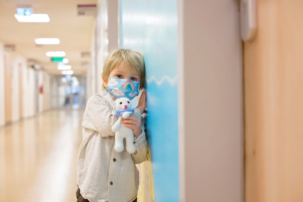 a child with a mask waiting in the ER hallway