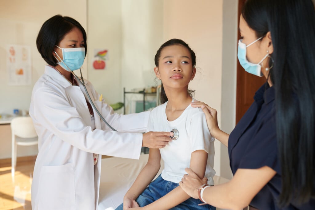 Teen girl in doctor's office with parent