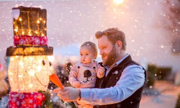a dad and young child look at a snowman at the OKM Christkindl Market