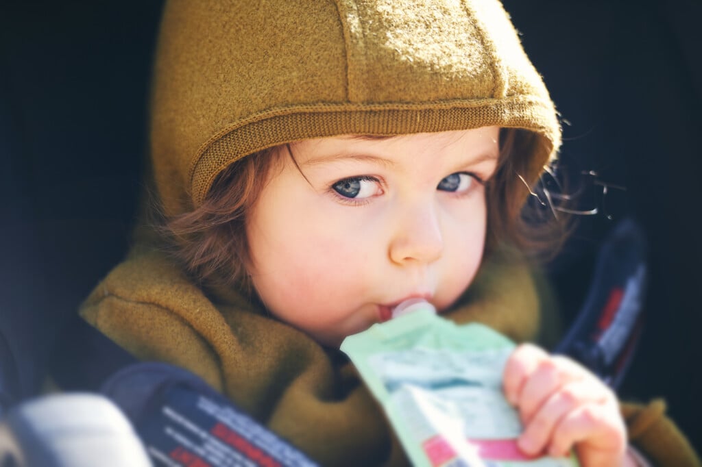 toddler eating out of a fruit pouch