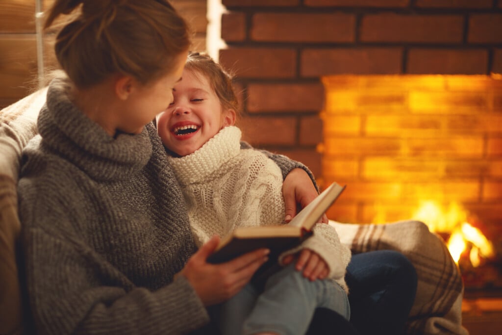 mom and daughter reading together by the fire