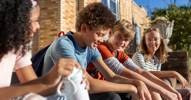 Teens sitting outside and smiling, from the TSET Healthy Youth Initiative