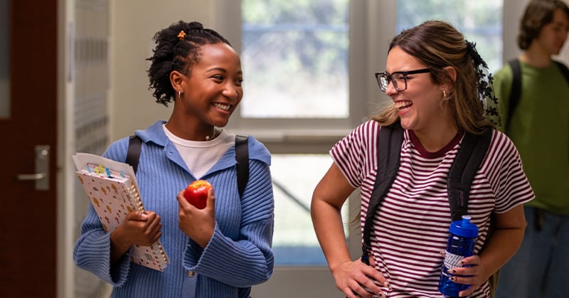 two smiling teens in hallway