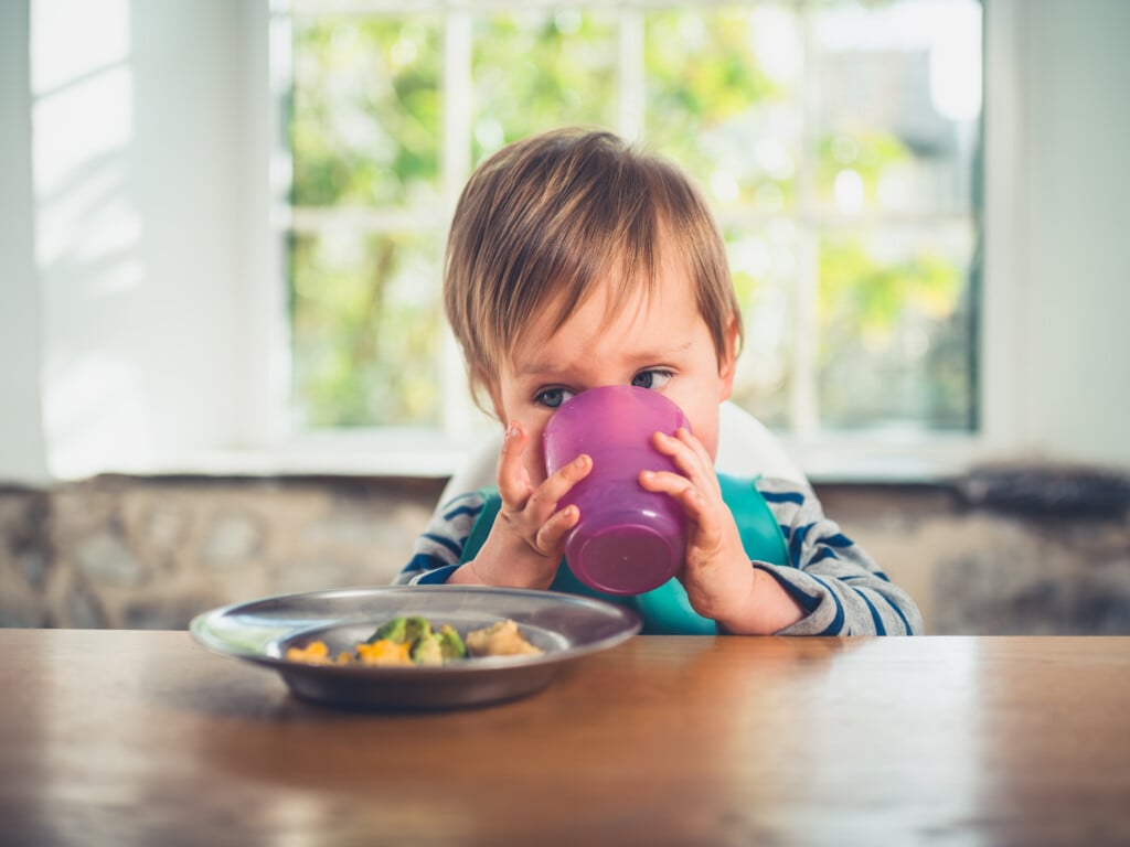 a young boy showing independence by drinking from a cup