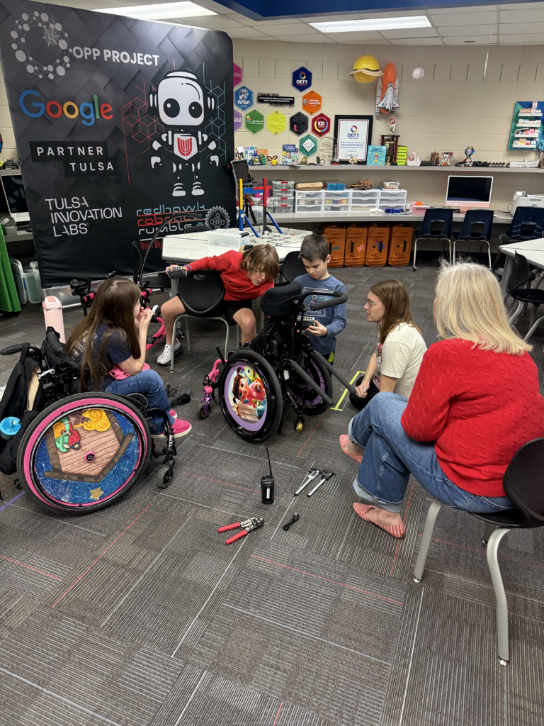 Students who have participated in the Darnaby Elementary Tech and Robotics Club pathway place sensor devices on the wheelchair.