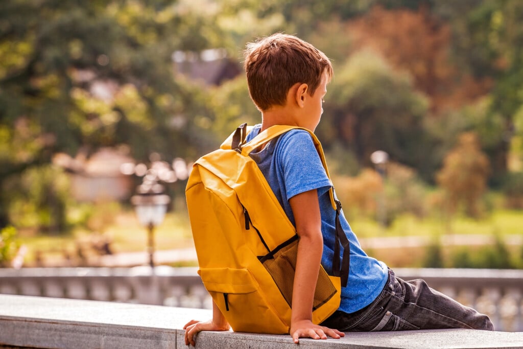 boy sitting alone with backpack
