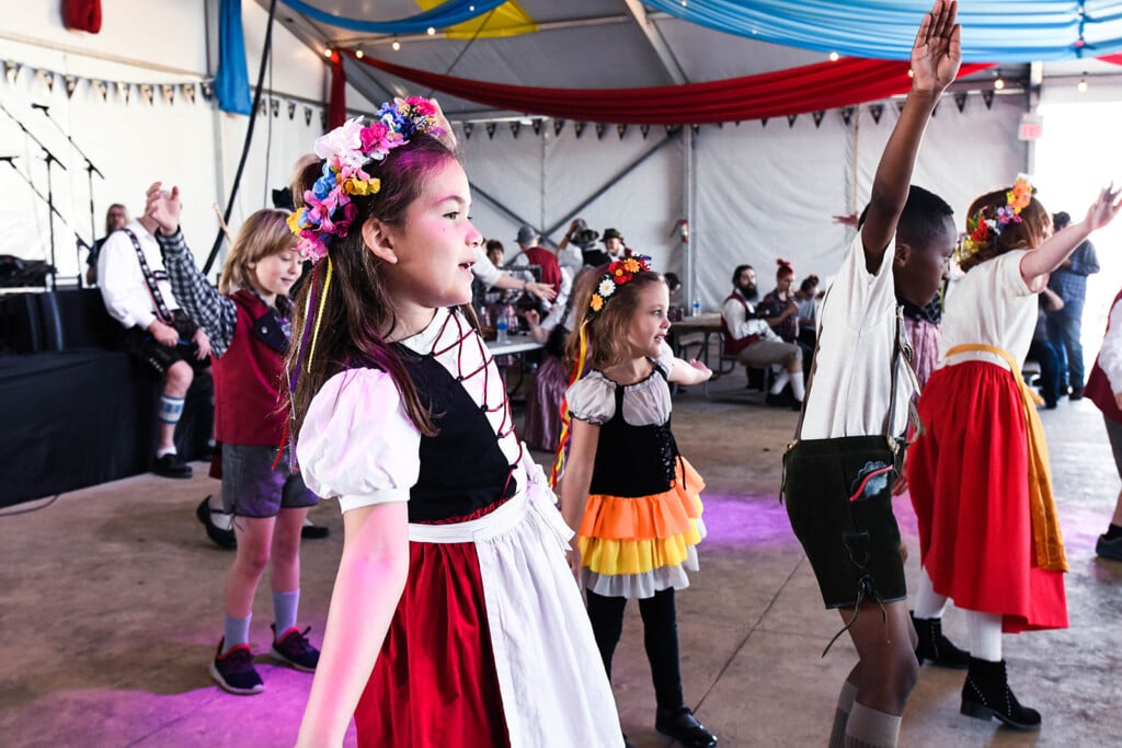 girls dancing at an oktoberfest celebration in traditional German outfits