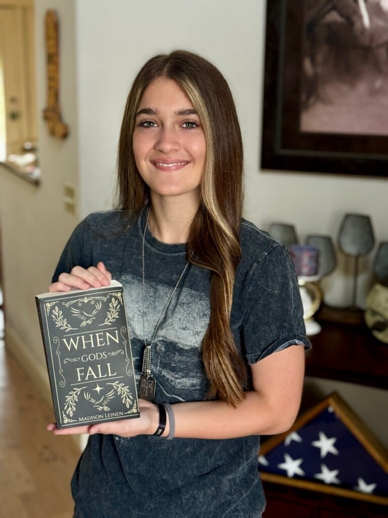 Madison Leinen holding her book, When Gods Fall