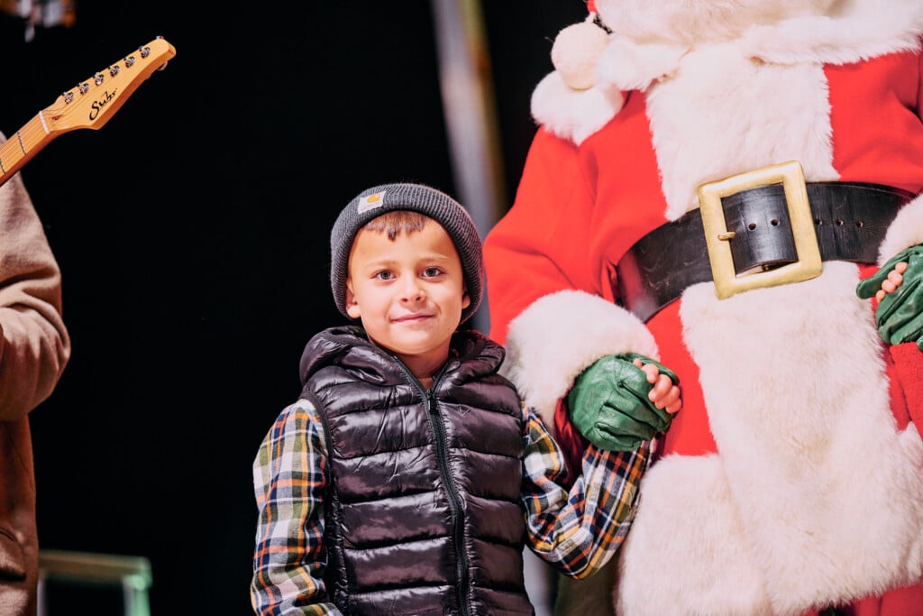 a boy holds Santa's hand at lights on at utica square
