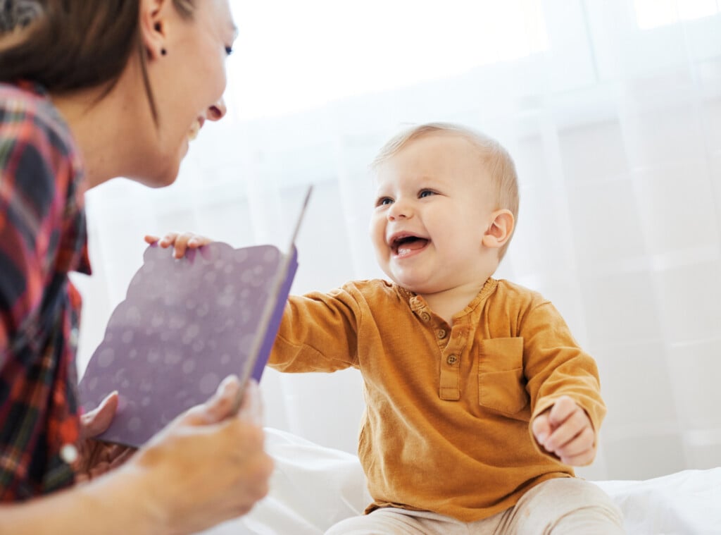 a mother and child reading a book together and smiling