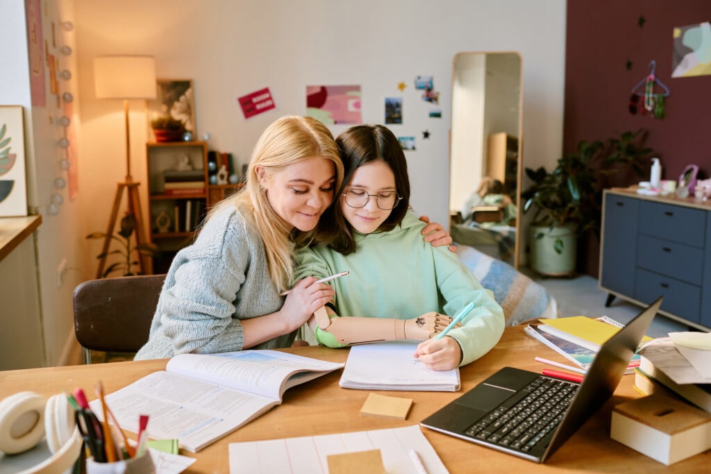 a mother and daughter working at computer desk together