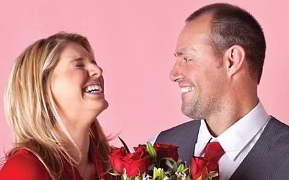 woman and man smiling at each other with roses, for article on recharge your relationship