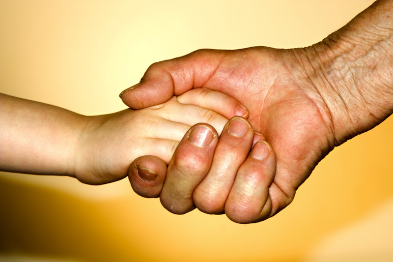 young hand holding older hand, for article on grandparents raising grandchildren