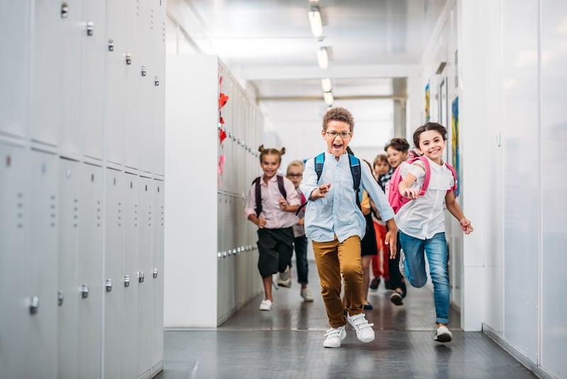 Kids running down a hallway lined with lockers. For a list of back to school events in Tulsa