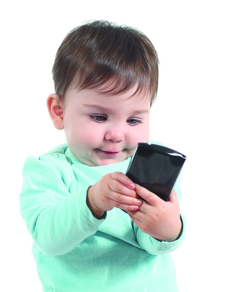 young child holding cell phone. for article on screen time and speech development