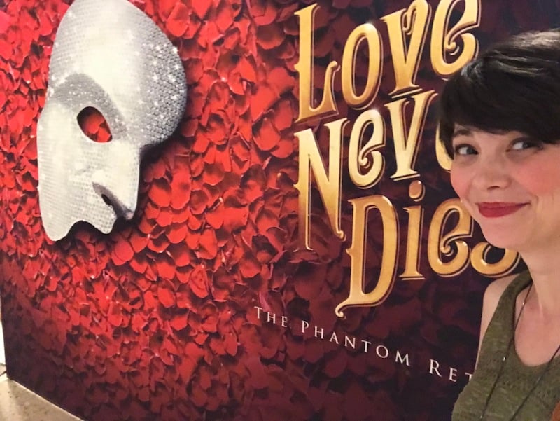 tara rittler in front of a love never dies photo backdrop