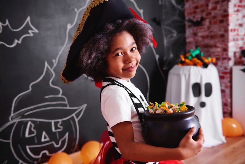girl dressed as pirate holding candy, for list of halloween events in tulsa