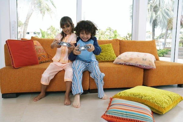 brother and sister playing on a couch, for article on sibling rivalry