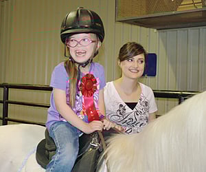 a young girl sits upon a horse at bit by bit