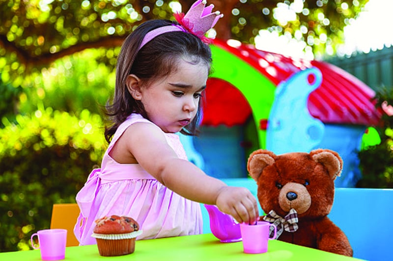 young girl having a tea party with a stuffed bear