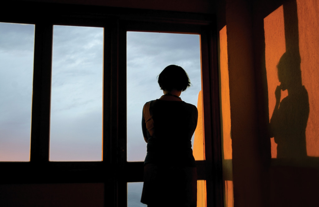 woman sillhouetted against window. post-partum depression concept