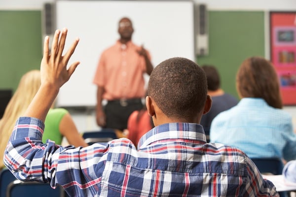 boy raises hand in classroom, for article on gifted students