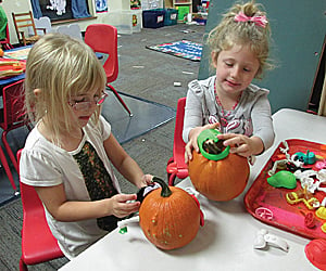 two young girls decorate pumpkins for article on wee ministry