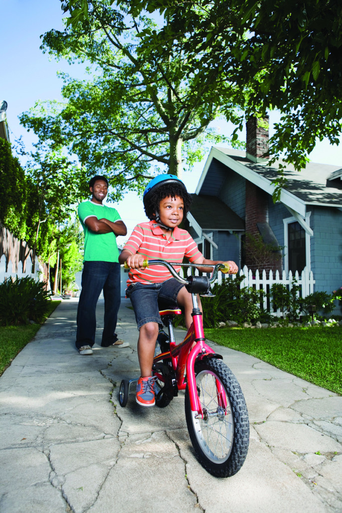 child riding a bike with dad looking on, for article on resiliency