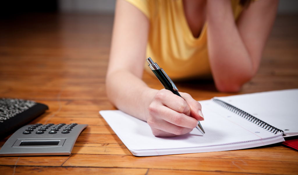 young woman's arm over notebook, holding pencil, life skills for teens concept