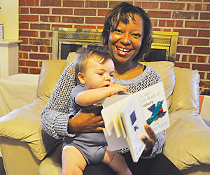 jackie lee, founder of a home daycare, holds a baby and picture book