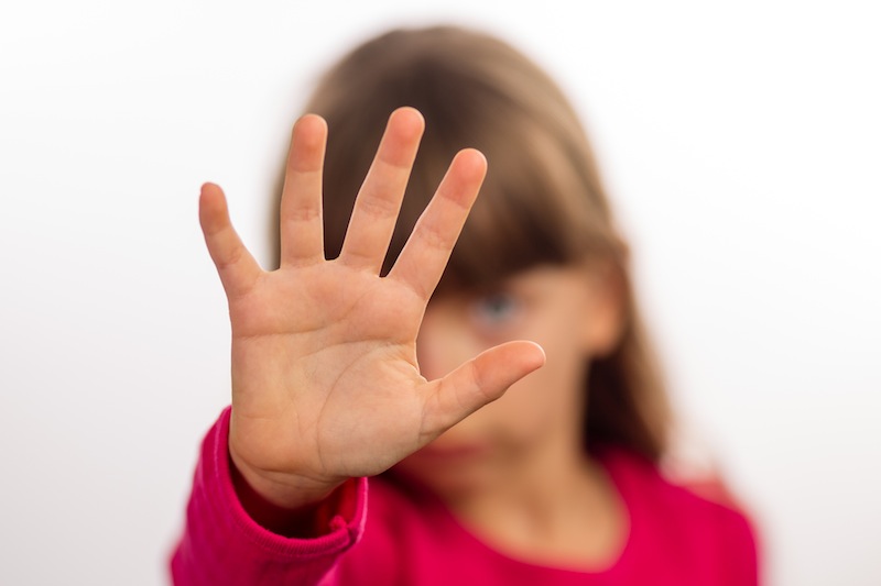 girl with hand in front of face, for article on how to protect children from sexual abuse