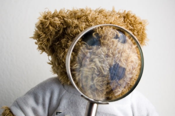 teddy bear holding magnifying glass, for article on toddler head injuries