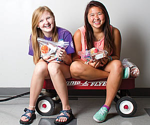 volunteering image, two girls sit in a wagon, smiling
