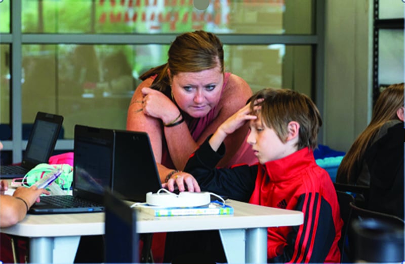 teacher explains assignment to frustrated kid on laptop, for article on self-paced learning