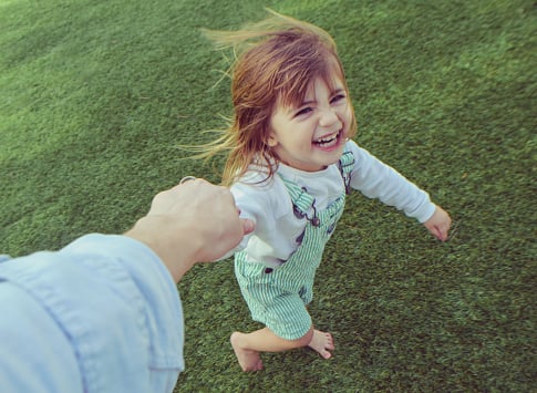 young girl playing outside and holding adult's hand, for article on how children should be seen and heard