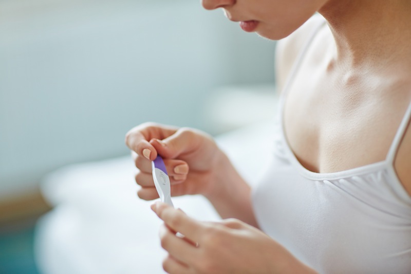 young woman holding pregnancy test for article on teen pregnancy in oklahoma