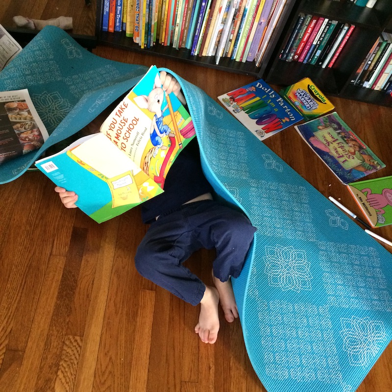 joss rittler reading a book under a yoga mat, for article about cosmic kids yoga