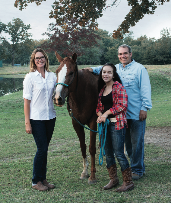 a man, woman and teenage girl stand with a horse at tulsa hills youth ranch