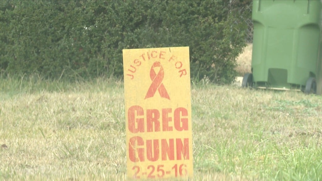 A sign sits in Greg Gunn's mothers front yard, just a few feet from where he was shot and killed.