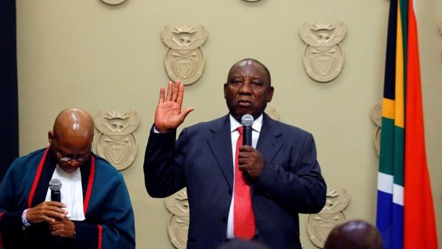 South Africa's new president Cyril Ramaphosa (R) holds up his right hand as he is sworn into office by South Africa's Chief Justice Mogoeng Mogoeng (L) after being elected by the Members of Parliament at the Parliament in Cape Town