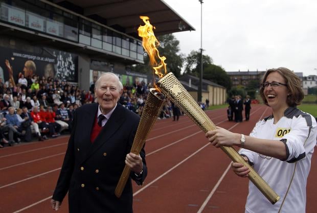 The Olympic Flame is passed between Sir Roger Bannister and Oxford doctoral student Nicola Byrom on the running track at Iffley Road Stadium in Oxford