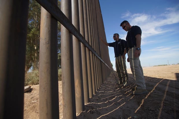 Border Patrol agents stand along the border fence on April 6